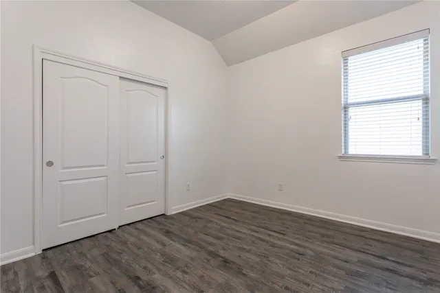 an empty room with wooden floor and window