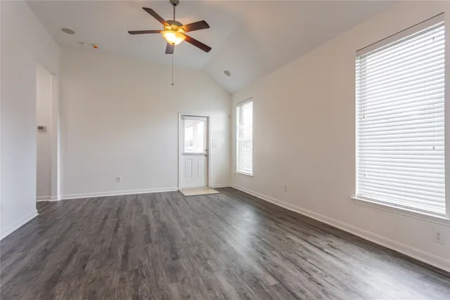 a view of empty room with wooden floor and fan
