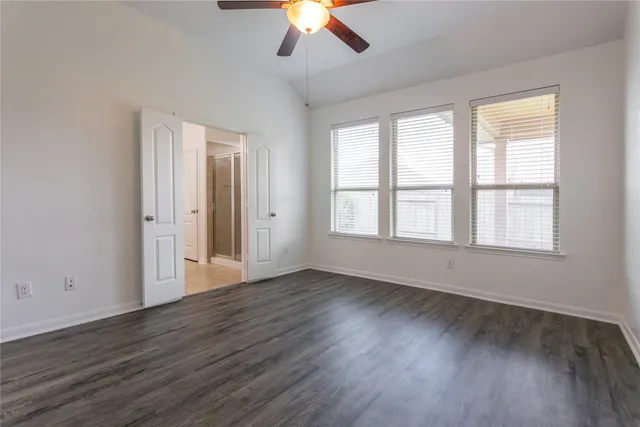an empty room with wooden floor chandelier and windows