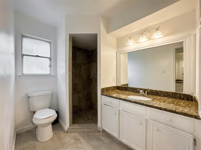 a spacious bathroom with a granite countertop toilet sink and mirror