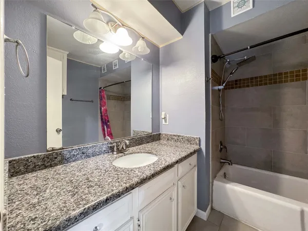 a bathroom with a granite countertop sink a mirror a vanity and bathtub