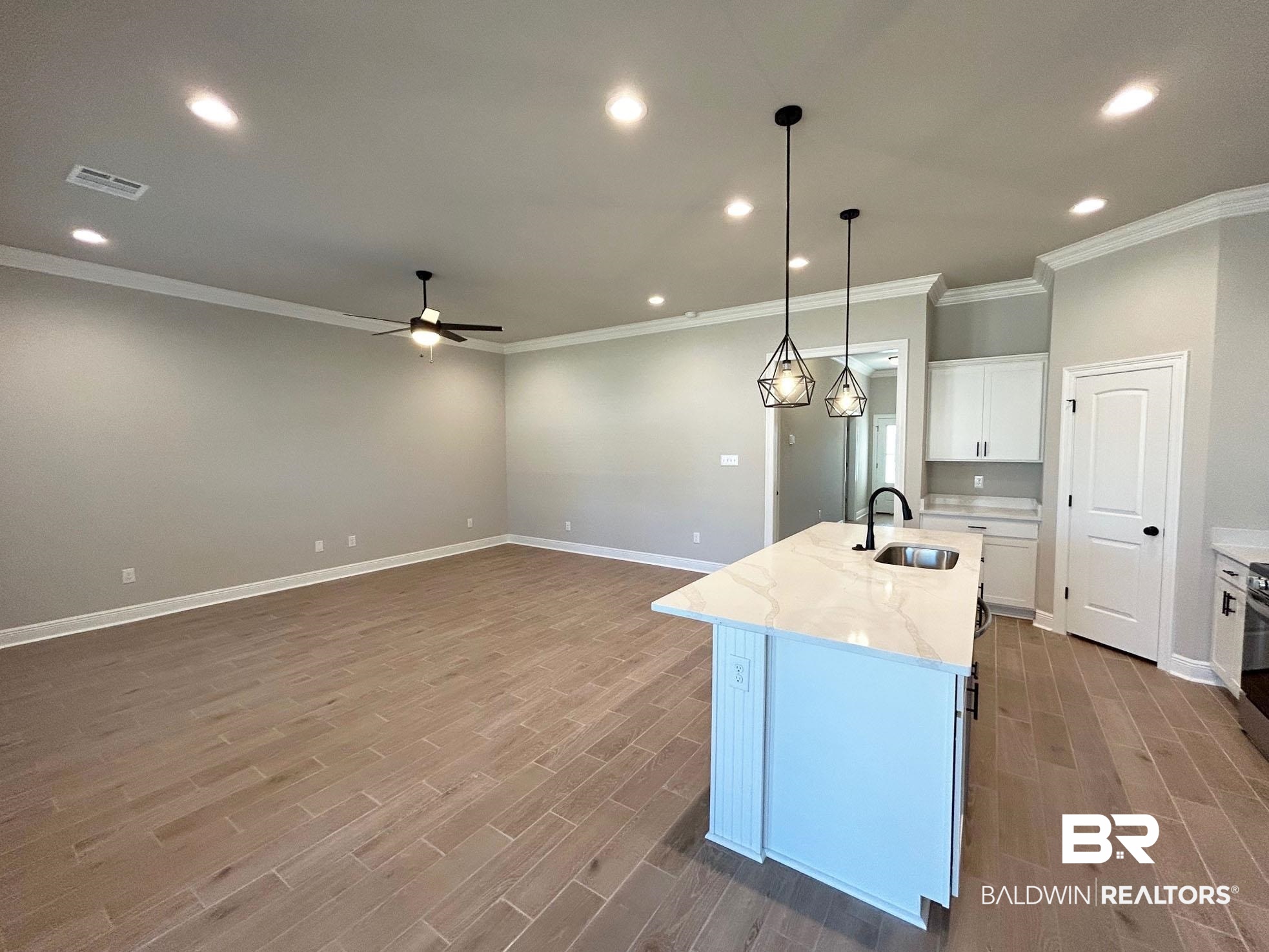 877 Sumter Loop Foley, AL 36535 - Photo 4 of 18 Kitchen with visible vents, a kitchen island with sink, a sink, wood finished floors, and white cabinetry