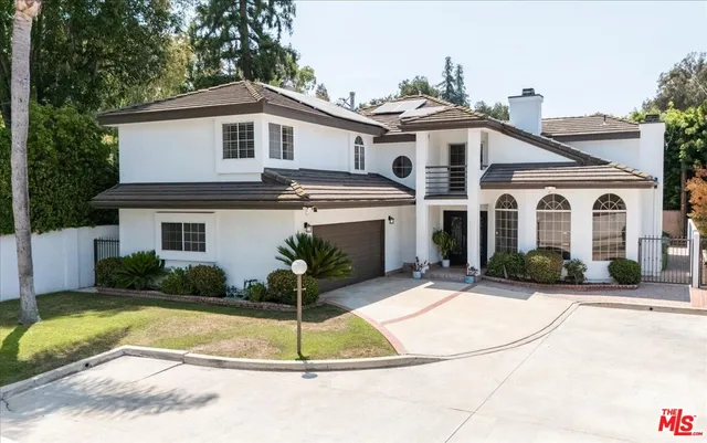 a front view of a house with a yard and potted plants