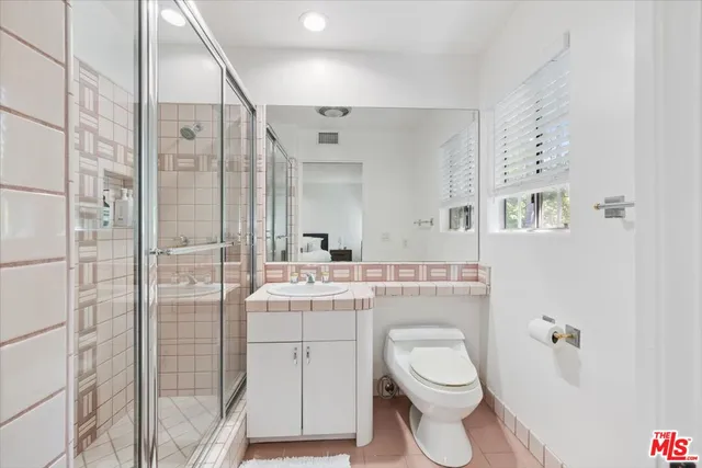 a bathroom with a granite countertop sink a toilet a mirror and shower