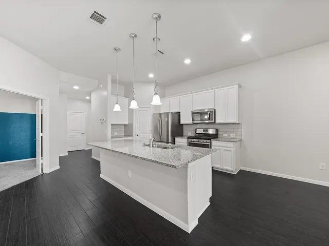 a kitchen with stainless steel appliances kitchen island granite countertop a stove a sink and a refrigerator