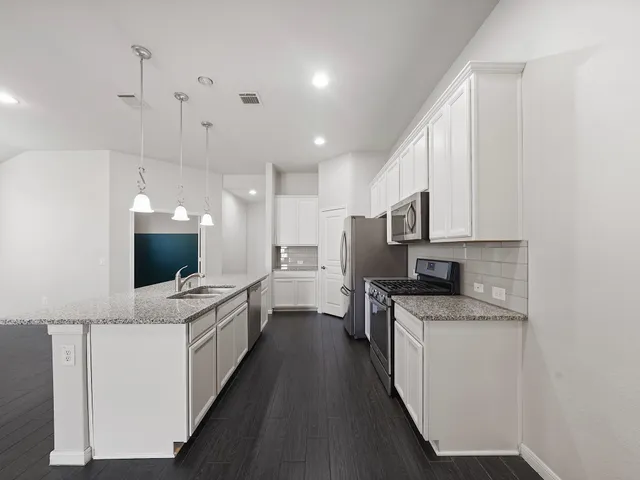 a kitchen with a sink a counter top space stainless steel appliances and cabinets