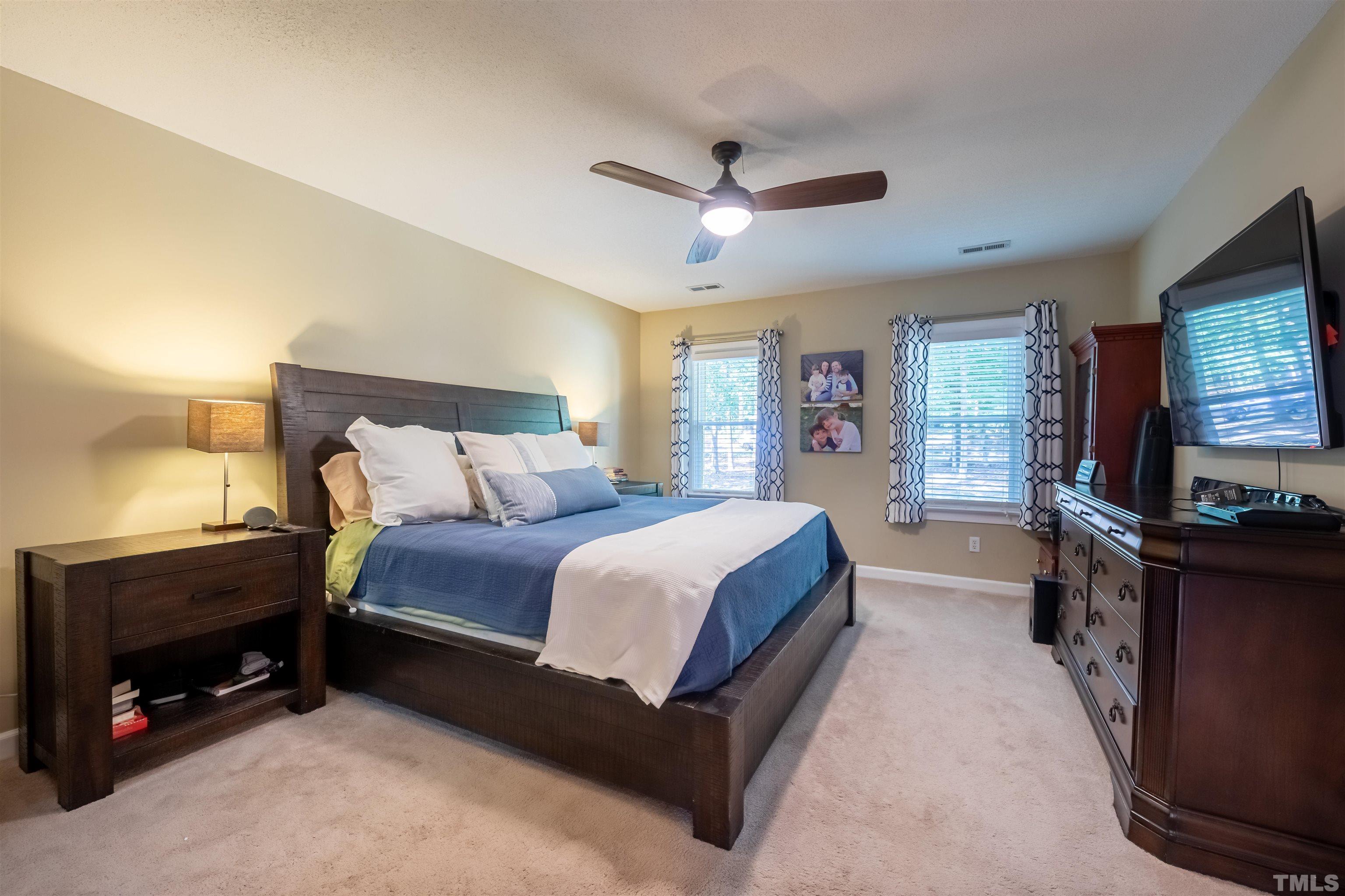 11308 Derby Lane Raleigh, NC 27613 - Photo 22 of 42 a spacious bedroom with a bed and a flat tv screen on dresser