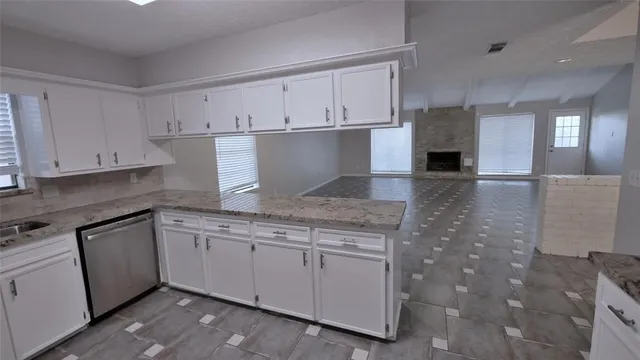 a kitchen with granite countertop a sink and white cabinets