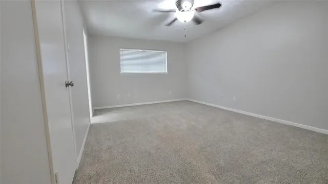 an empty room with a chandelier fan and windows
