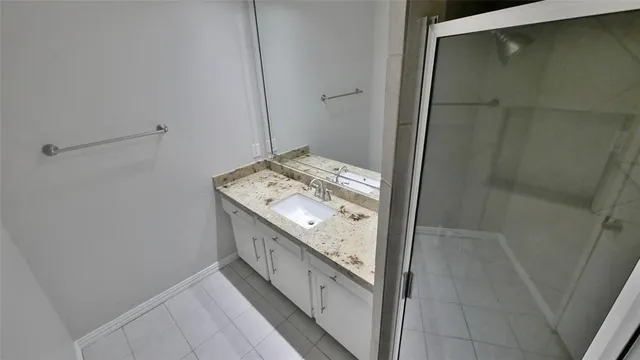 a bathroom with a granite countertop sink a mirror and shower