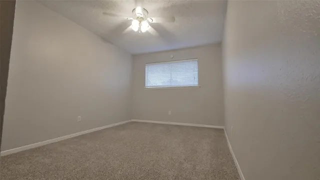 an empty room with a chandelier fan and windows