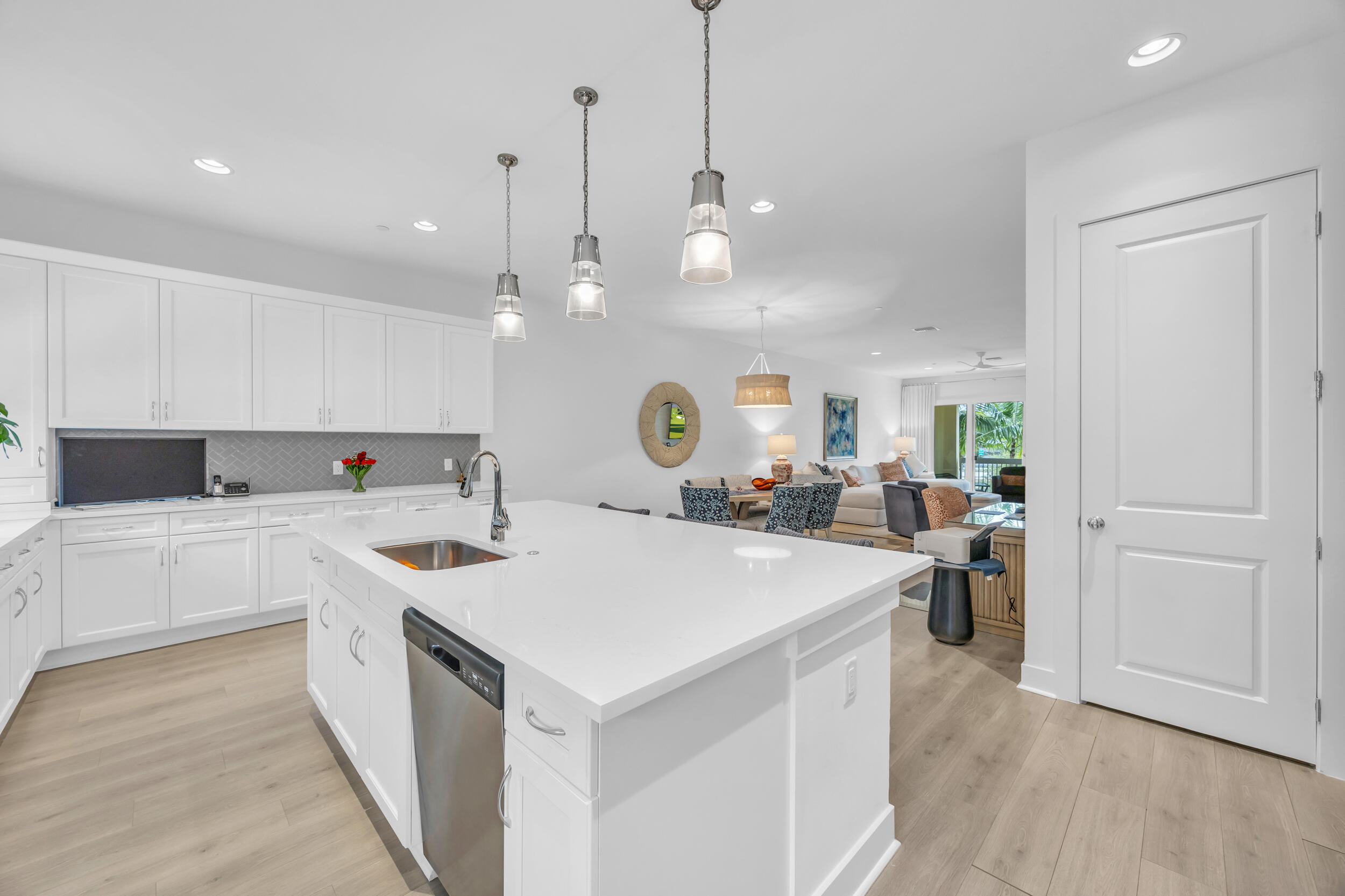 12554 Gross Pointe Road Palm Beach Gardens, FL 33418 - Photo 18 of 39 a large kitchen with kitchen island a sink dishwasher a stove a refrigerator and white cabinets with wooden floor