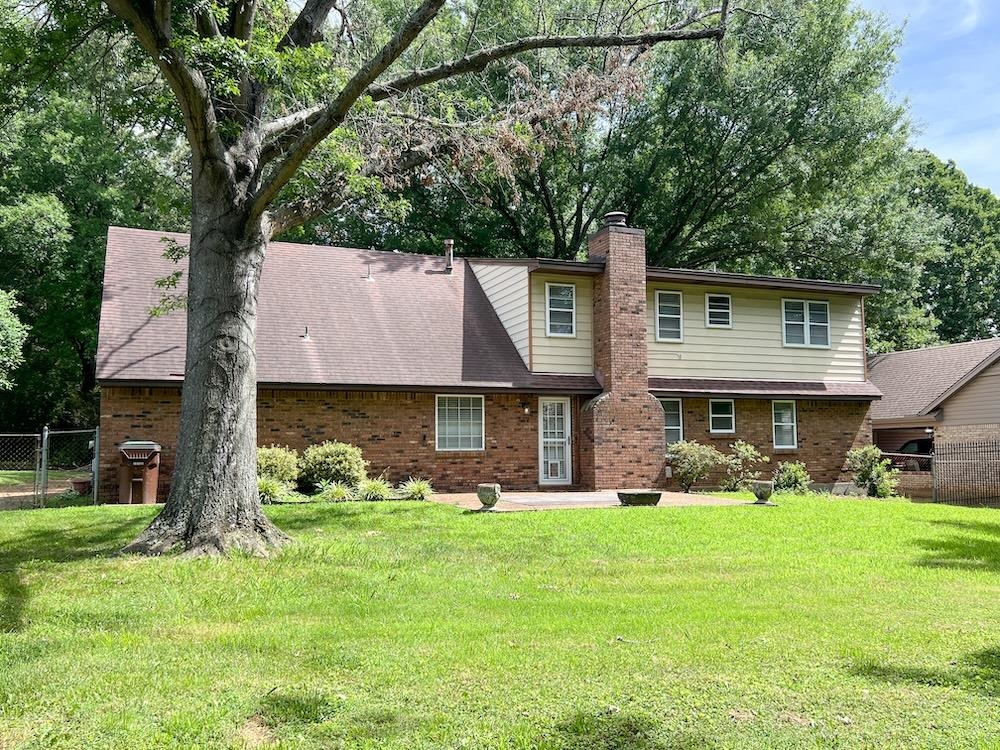 7935 Memphis Arlington Road Bartlett, TN 38133 - Photo 18 of 20 Expansive grass lawn with a brick and siding exterior, a prominent brick chimney, and mature trees providing natural shade