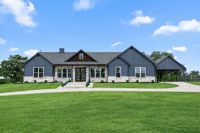 a front view of a house with a garden and trees
