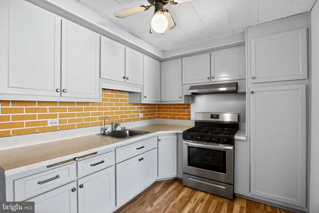 a kitchen with granite countertop a stove a sink and dishwasher wooden cabinets