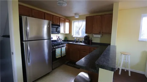 a kitchen with stainless steel appliances granite countertop a refrigerator a stove a sink and with a dining table