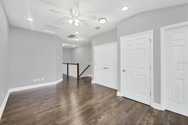 an empty room with wooden floor and ceiling fan