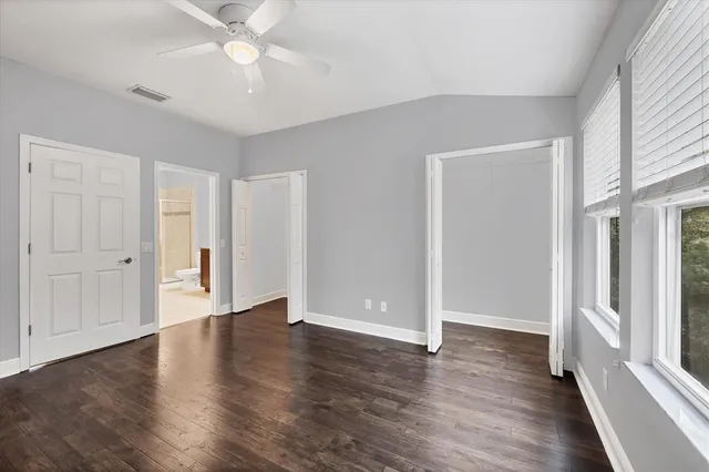 an empty room with wooden floor fan and windows