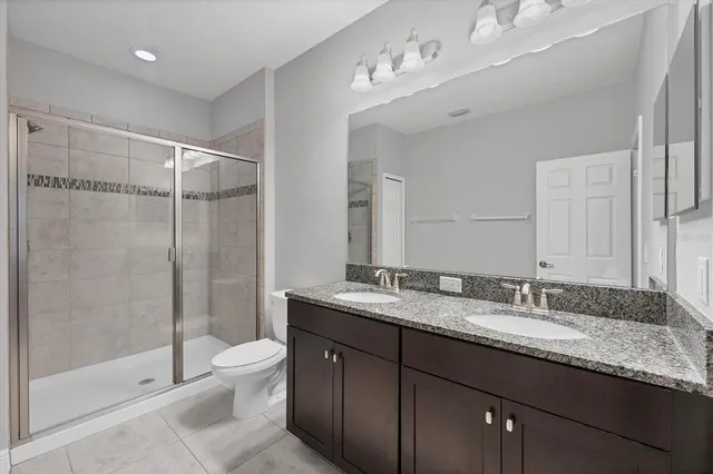 a bathroom with a granite countertop sink a toilet a mirror and shower