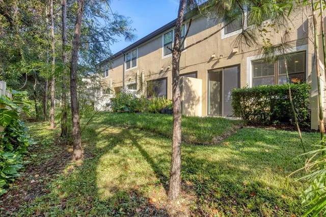 a view of a big yard in front of a brick house with large windows
