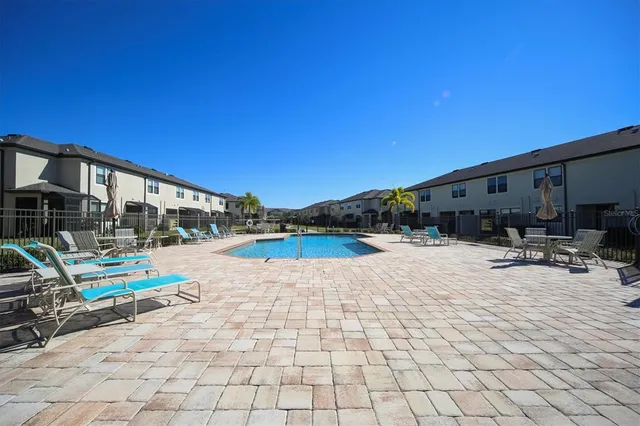 a view of swimming pool with lounge chair and dinning table under an umbrella