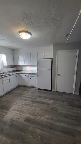 a kitchen with granite countertop a refrigerator and a stove top oven
