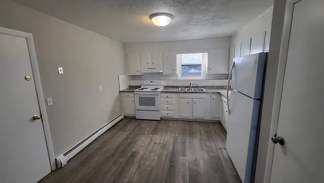 a kitchen with stainless steel appliances granite countertop a refrigerator a sink dishwasher a stove and white countertops with wooden floor