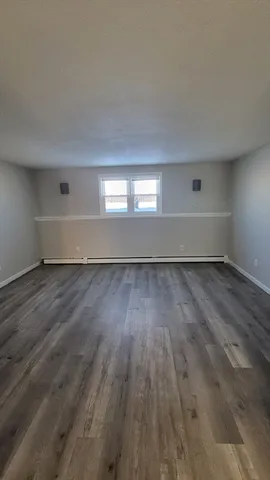a view of empty room with wooden floor and white walls
