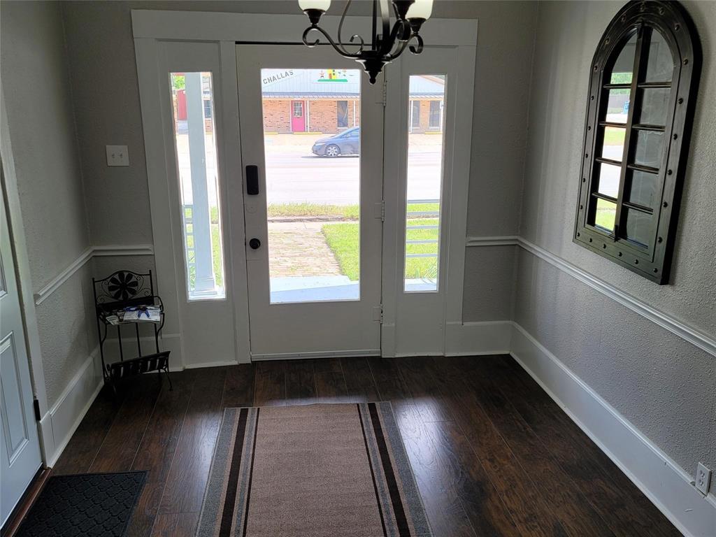 1103 East Moore Avenue, Unit 1 Terrell, TX 75160 - Photo 3 of 12 Foyer entrance with an inviting chandelier, a textured wall, dark wood-style floors, and baseboards