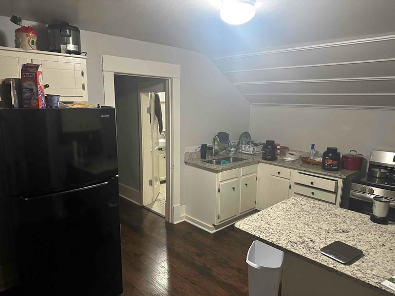 1103 East Moore Avenue, Unit 1 Terrell, TX 75160 - Photo 8 of 12 Kitchen with freestanding refrigerator, white cabinetry, stainless steel range oven, lofted ceiling, and light stone counters
