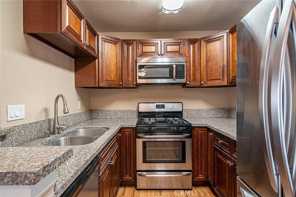 7720 Elmdale Way, Unit J Stanton, CA 90680 - Photo 5 of 18 a kitchen with granite countertop a sink stove and microwave