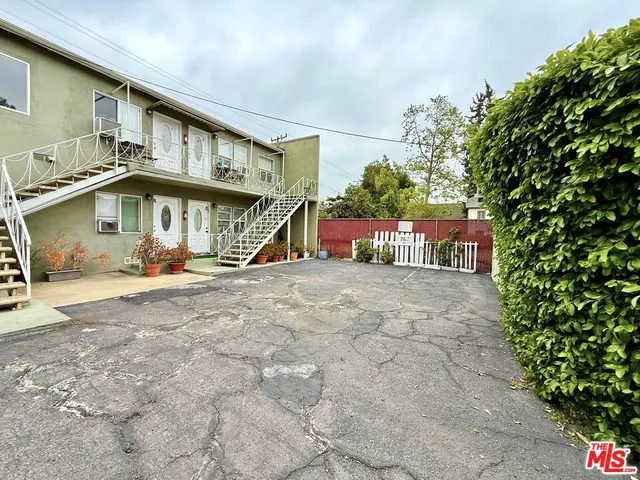 a view of a white house with large windows and a table and chairs under an umbrella