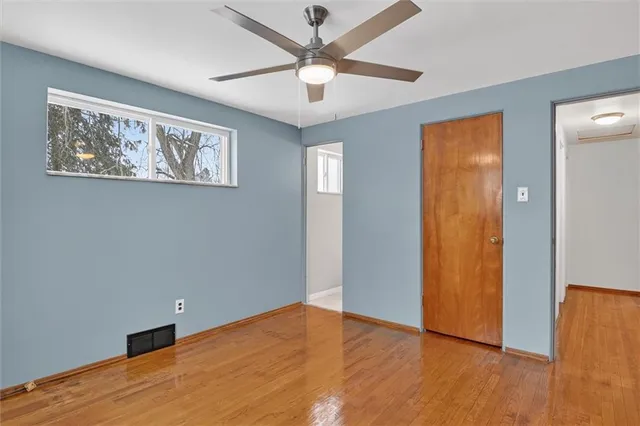 a view of an empty room with window and wooden floor