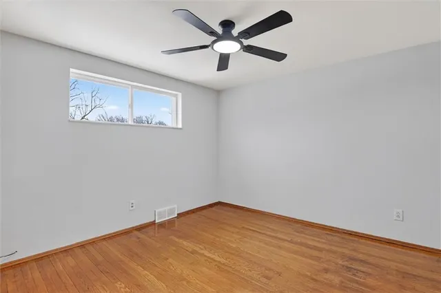 an empty room with a fan & a ceiling fan