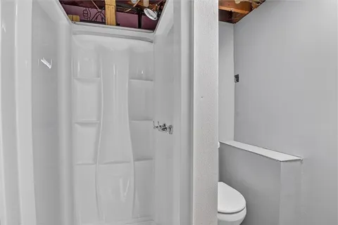 a white toilet sitting next to a shower
