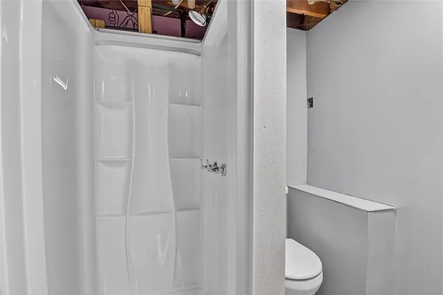 a white toilet sitting next to a shower