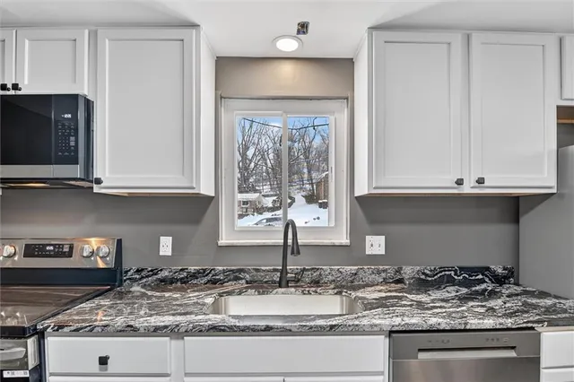 a kitchen with granite countertop a sink and a stove