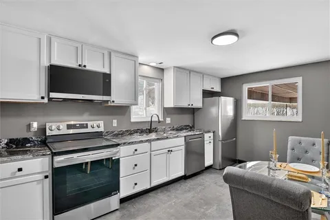 a kitchen with stainless steel appliances granite countertop a stove a sink and a microwave