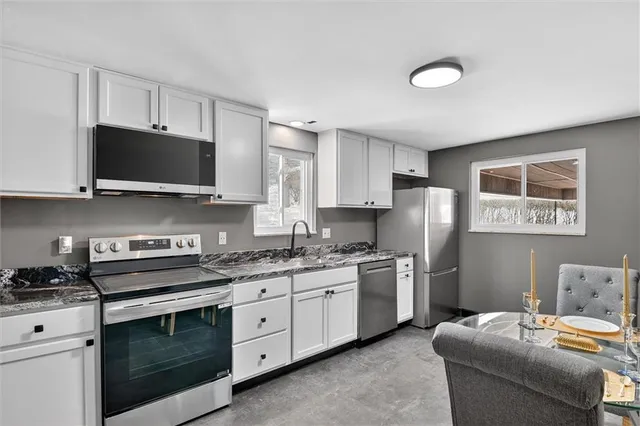 a kitchen with stainless steel appliances granite countertop a stove a sink and a microwave