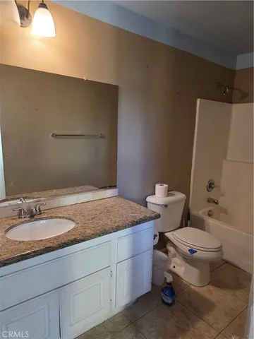 a bathroom with a granite countertop sink a toilet and a mirror