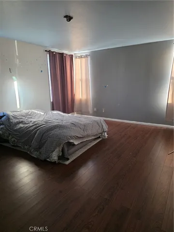 a spacious bedroom with a bed and wooden floor