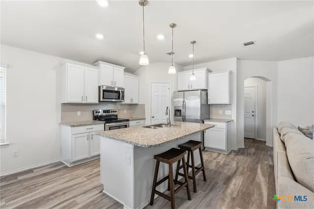 a kitchen with stainless steel appliances granite countertop a stove a refrigerator a oven a sink with a dining table and chairs