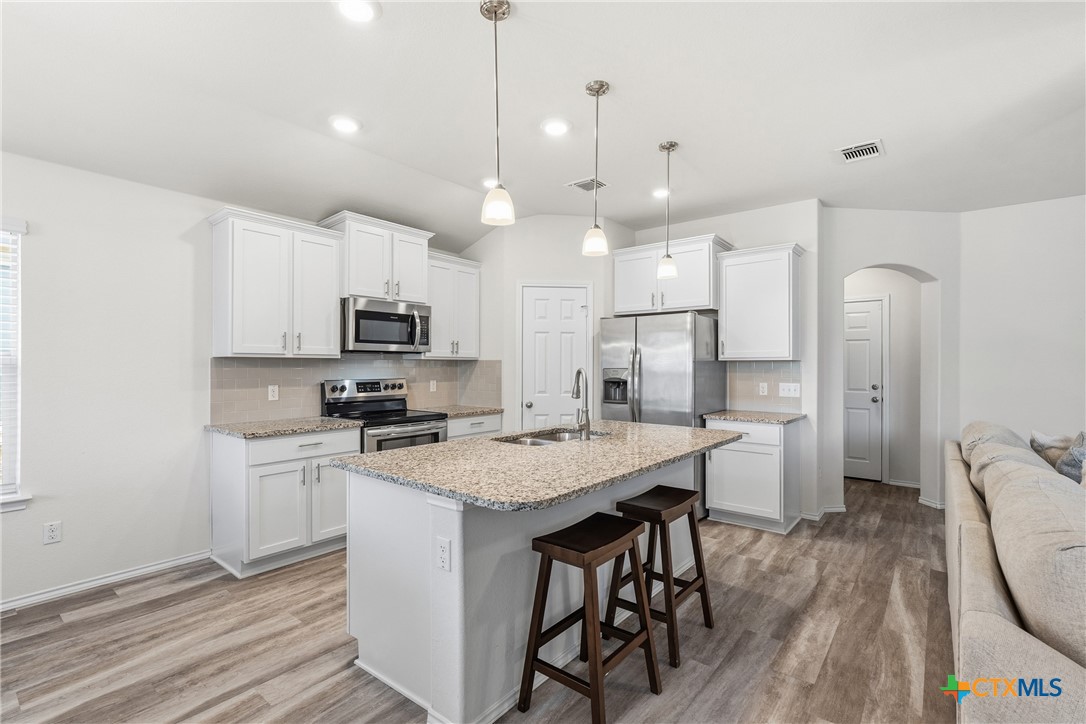 212 Bainbridge Road Temple, TX 76502 - Photo 11 of 35 a kitchen with stainless steel appliances granite countertop a stove a refrigerator a oven a sink with a dining table and chairs