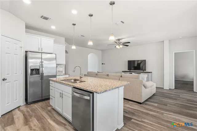 a large white kitchen with a sink and a refrigerator