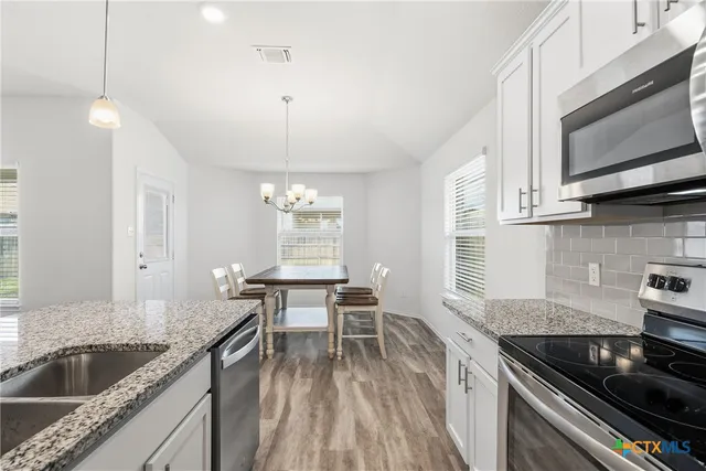 a kitchen with granite countertop a stove a sink and a wooden cabinets