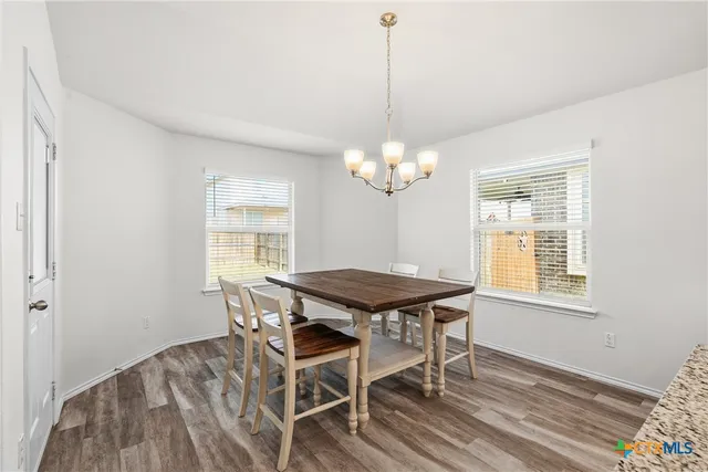 a dining room with chandelier and wooden floor