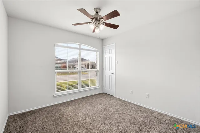 an empty room with windows and ceiling fan