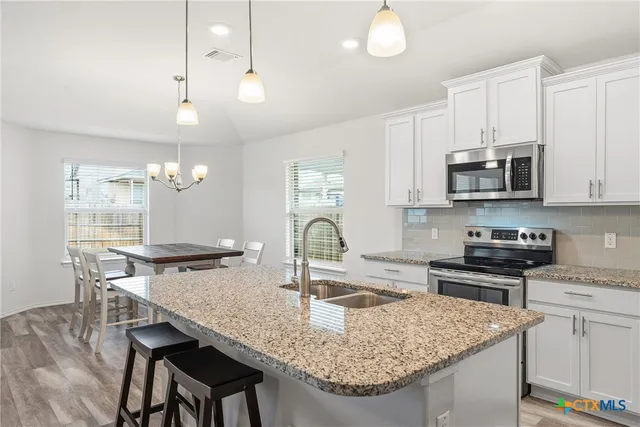 a kitchen with granite countertop a stove a sink and a microwave