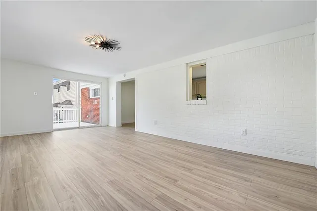 a view of an empty room with wooden floor and a fan