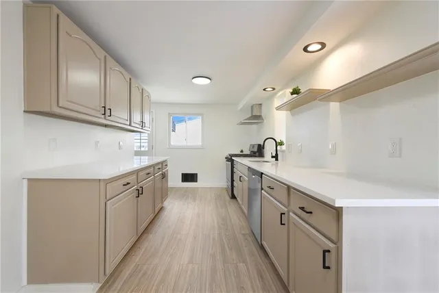 a kitchen with granite countertop a sink dishwasher stove and cabinets with wooden floor